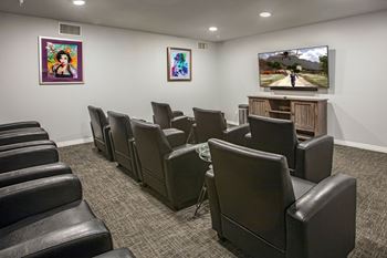 A room with black leather chairs and a television playing a game.